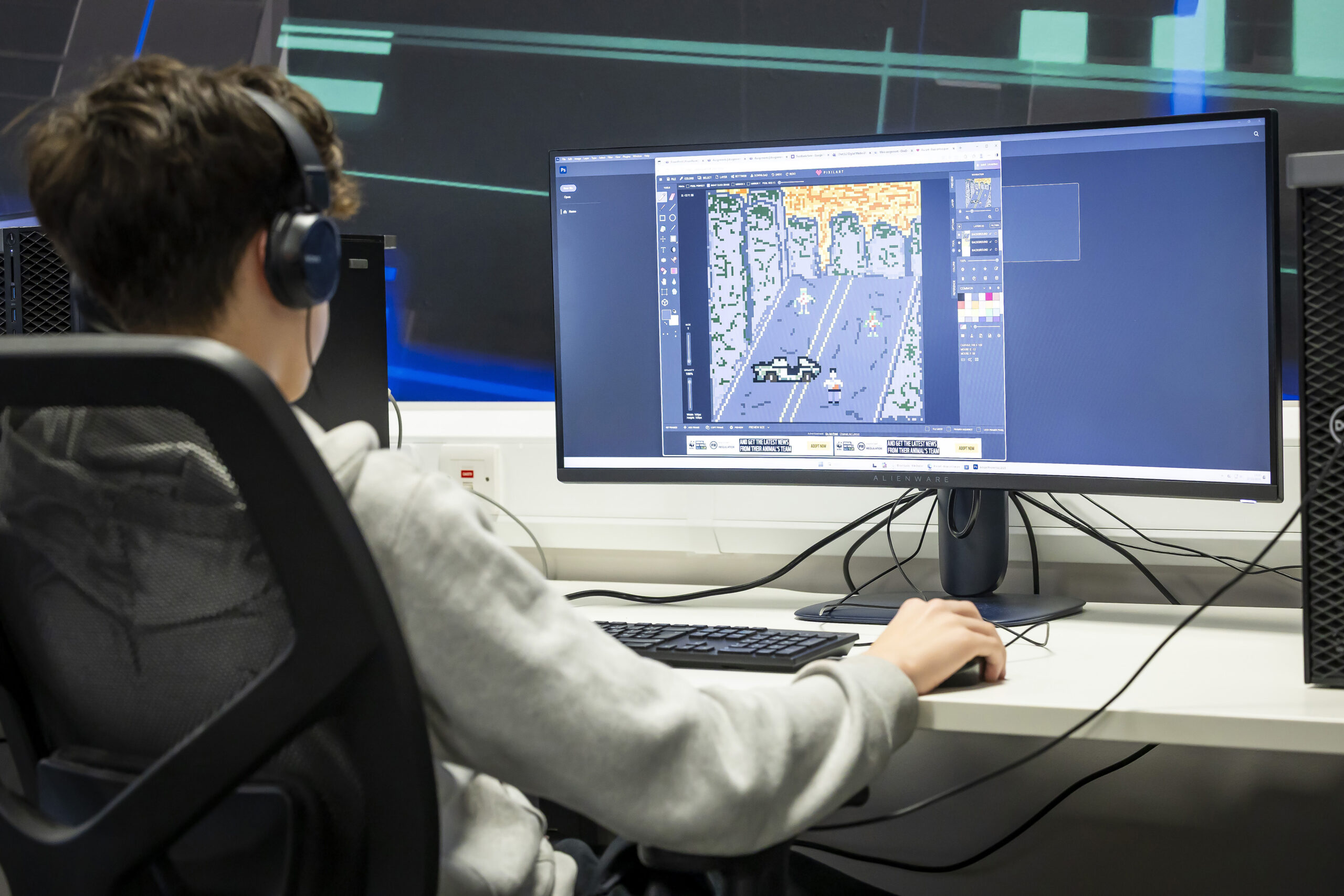 Student using a desktop computer to develop pixel art graphics as part of a computing application development course.